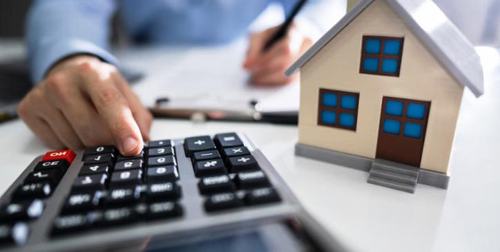 Close-up Of A Person Hand Calculating A Real Estate Property Tax On Wooden Desk Close-up Of A Person Hand Calculating A Real Estate Property Tax On Wooden Desk